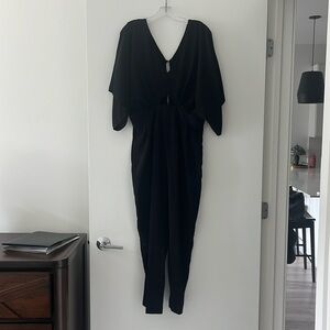 Black jumpsuit with wide v neck detail, flutter sleeves and cutout.